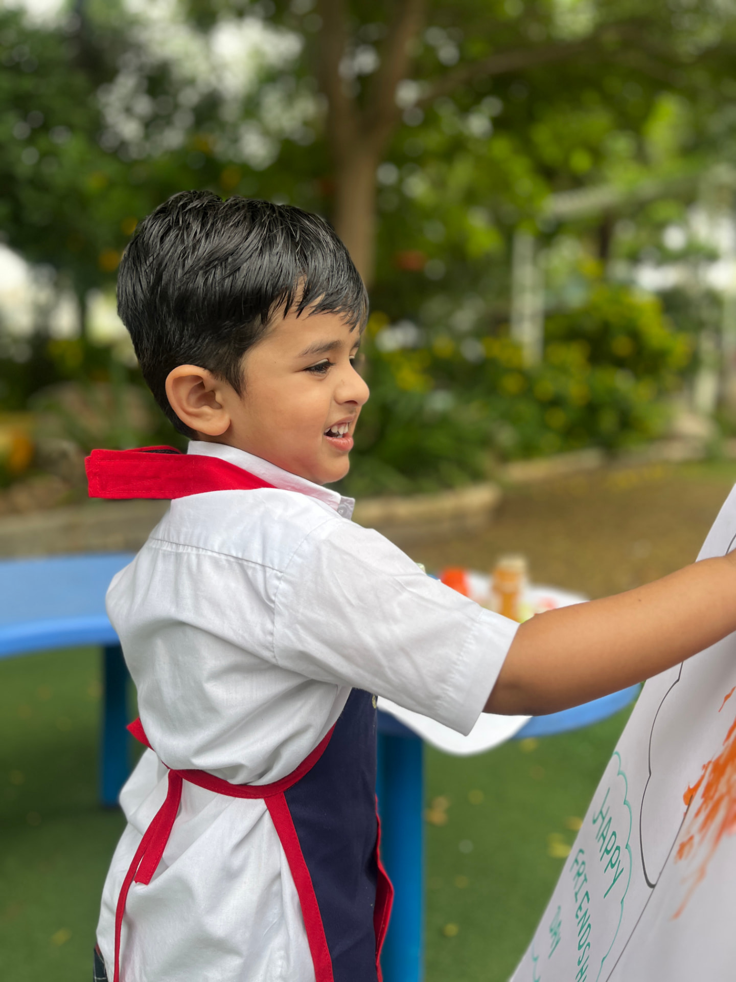 A young boy painting a Friendship Day poster outdoors